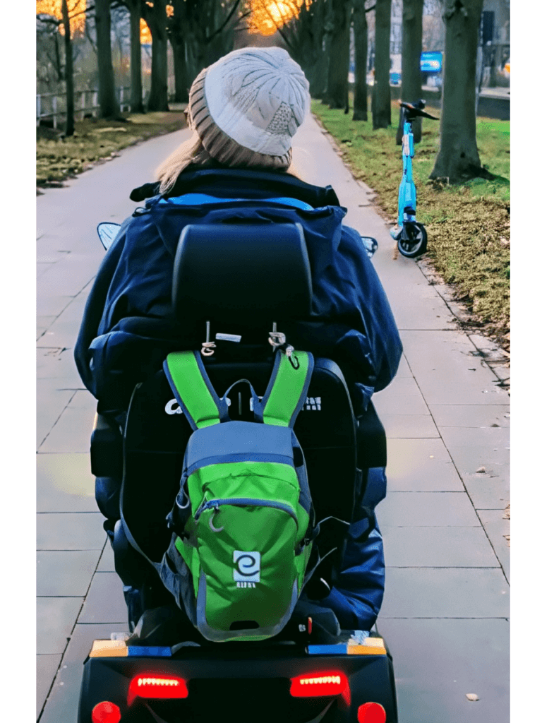 Frau sitzt auf einem Elektromobil mit Eifel Trekking Rucksack an der Rückenlehne und fährt die Rheinpromenade entlang.