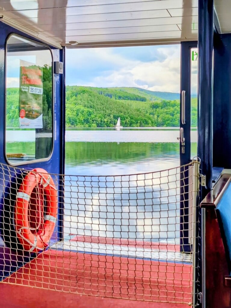Blick vom Innendeck der Stella Maris auf den Rursee und die bewaldeten Hügel der Eifel.