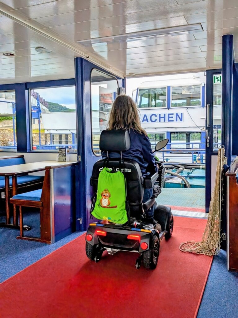 Rollstuhlfahrerin mit Elektromobil im Innenbereich der Stella Maris während der Rursee-Rundfahrt.